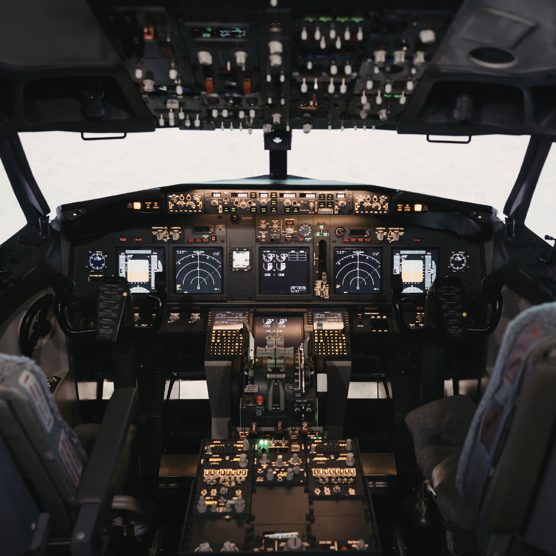 Fully equipped airplane cockpit with multiple displays, switches, and control columns.