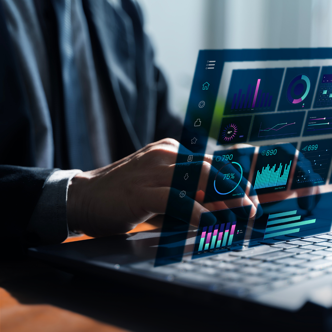 Businessperson using a laptop with translucent holographic dashboards displaying charts and graphs